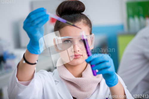 Image of female student with protective glasses making chemistry experime