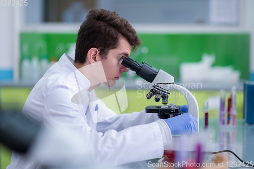 Image of student scientist looking through a microscope