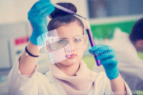 Image of female student with protective glasses making chemistry experime