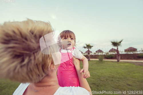 Image of mother and little daughter playing at backyard