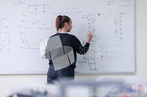 Image of female student writing on board in classroom