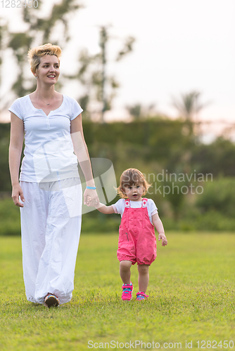 Image of mother and little daughter playing at backyard