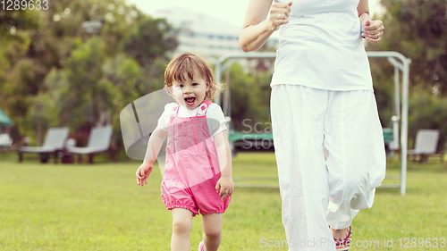 Image of mother and little daughter playing at backyard