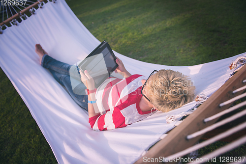 Image of woman using a tablet computer while relaxing on hammock