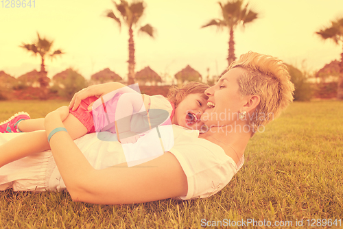 Image of mother and little daughter playing at backyard
