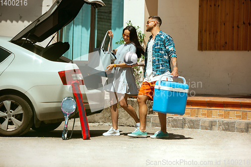 Image of Young couple preparing for vacation trip on the car in sunny day