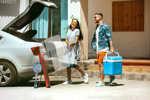 Image of Young couple preparing for vacation trip on the car in sunny day