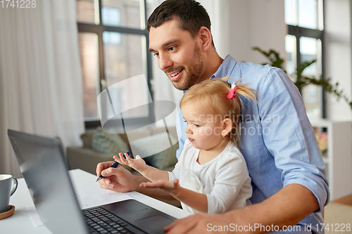 Image of working father with baby daughter at home office