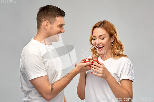 Image of happy couple in white t-shirts with christmas gift