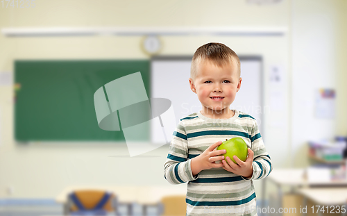 Image of smiling boy holding green apple at school