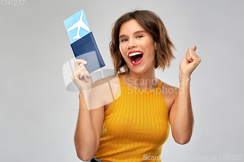 Image of happy young woman with air ticket and passport