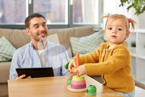 Image of father with tablet pc and baby daughter at home