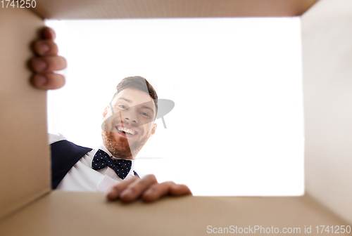 Image of happy young man looking into open gift box