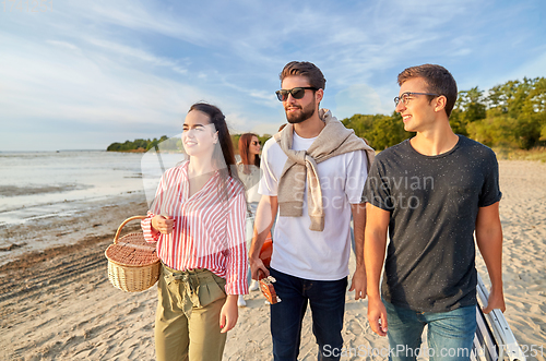 Image of happy friends walking along summer beach