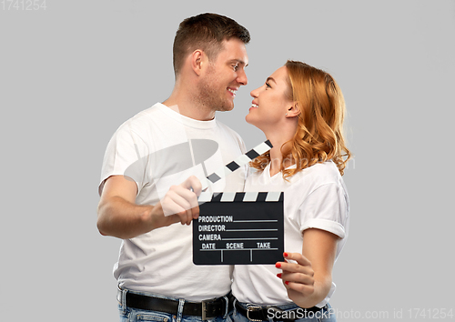 Image of happy couple in white t-shirts with clapperboard