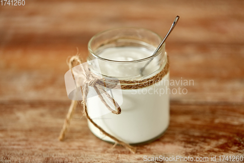 Image of yogurt or sour cream in glass jar on wooden table