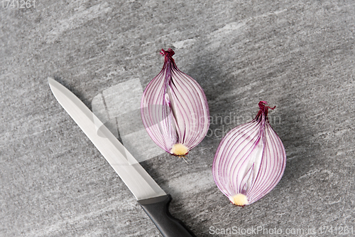 Image of cut red onion and knife on slate stone background