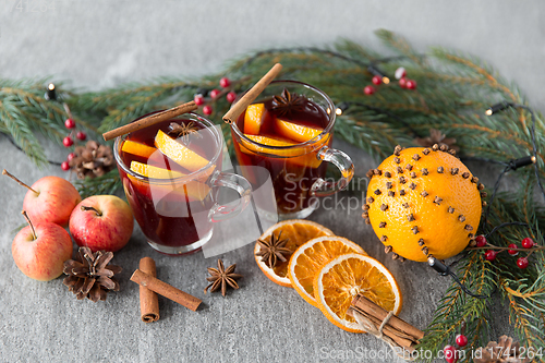 Image of glass of hot mulled wine, cookies, apples and fir