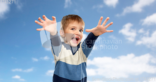 Image of little boy making scary faces over sky background