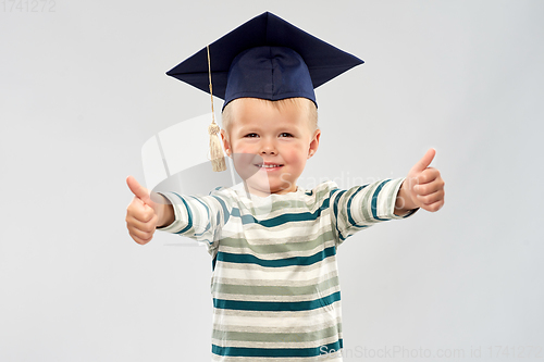 Image of happy little boy in mortar board showing thumbs up