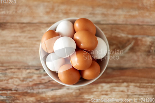 Image of close up of eggs in ceramic bowl on wooden table