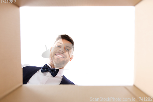 Image of happy young man looking into open gift box