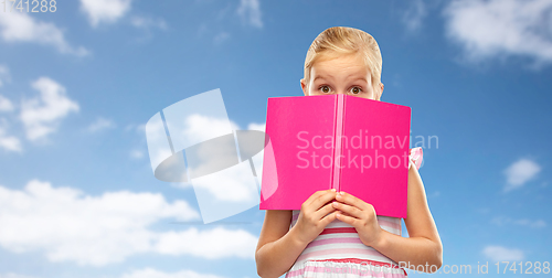 Image of little girl hiding over book on sky background