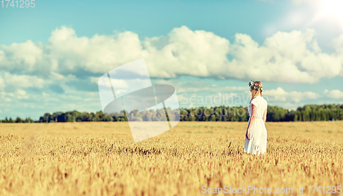 Image of happy young woman in flower wreath on cereal field