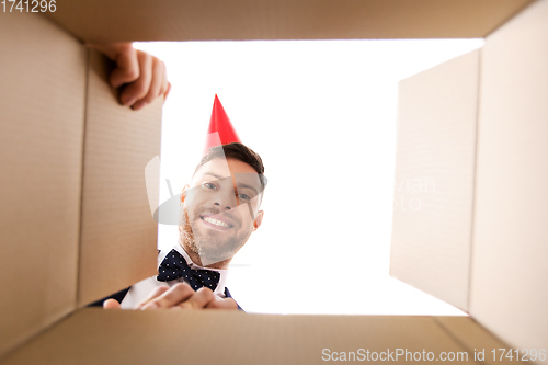 Image of happy young man looking into open birthday gift