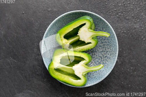 Image of cut green pepper in bowl on slate stone background