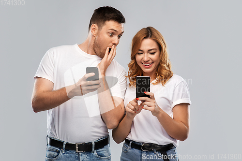 Image of happy couple in white t-shirts with smartphones