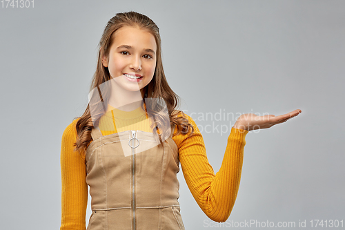 Image of happy teenage girl holding something on empty hand