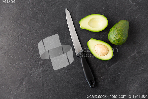 Image of avocados and knife on slate stone background