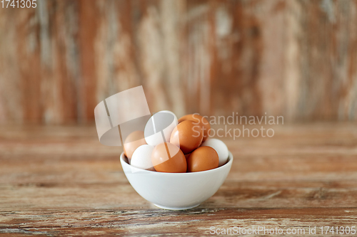 Image of close up of eggs in ceramic bowl on wooden table