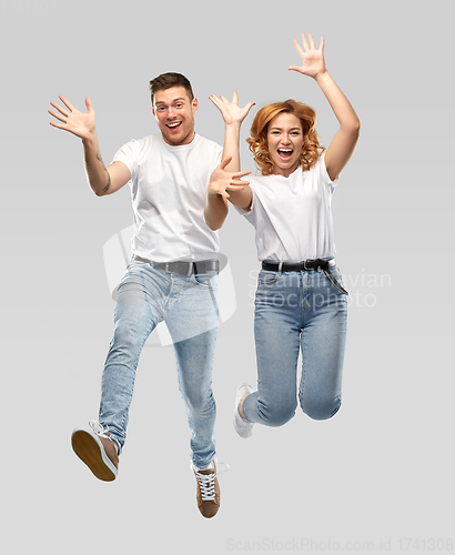 Image of happy couple in white t-shirts jumping