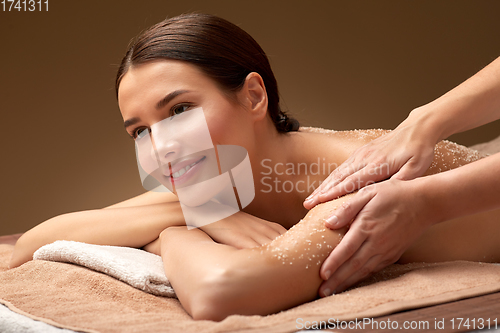 Image of happy woman having exfoliating salt massage at spa