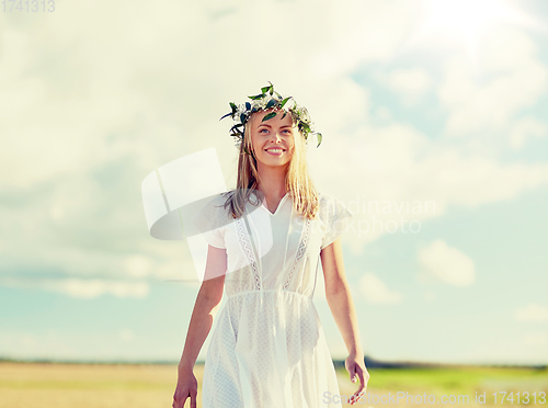 Image of smiling young woman in wreath of flowers outdoors