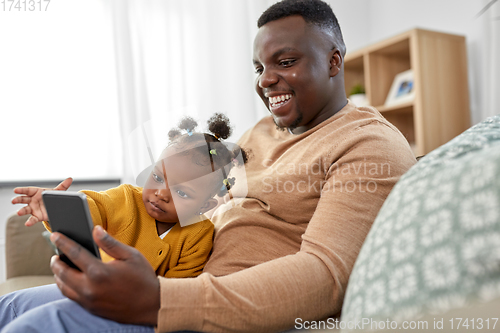 Image of father with smartphone and baby daughter at home