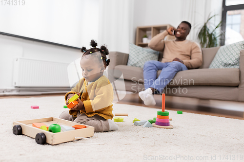 Image of african baby girl playing with toy blocks at home