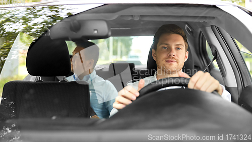 Image of male taxi driver driving car with passenger