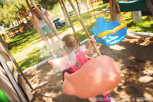 Image of mother and daughter swinging in the park