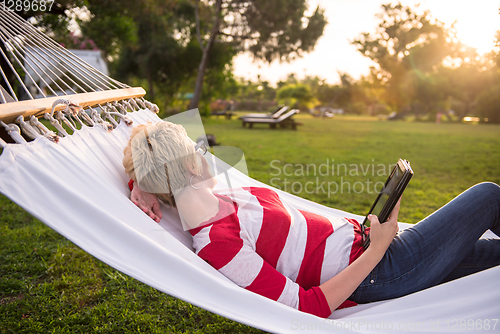 Image of woman using a tablet computer while relaxing on hammock