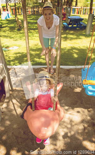 Image of mother and daughter swinging in the park