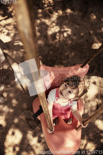 Image of little girl swinging  on a playground