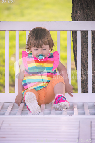 Image of cute little girl sitting on wooden bench