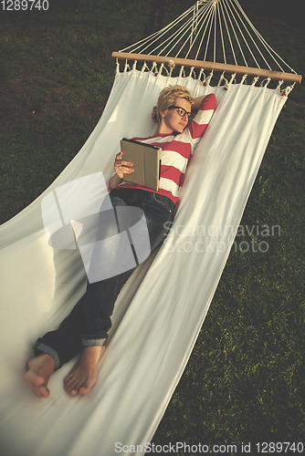 Image of woman using a tablet computer while relaxing on hammock