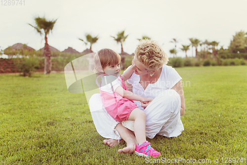 Image of mother and little daughter playing at backyard