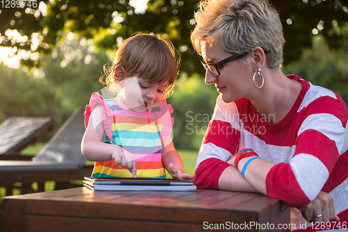 Image of mom and her little daughter using tablet computer