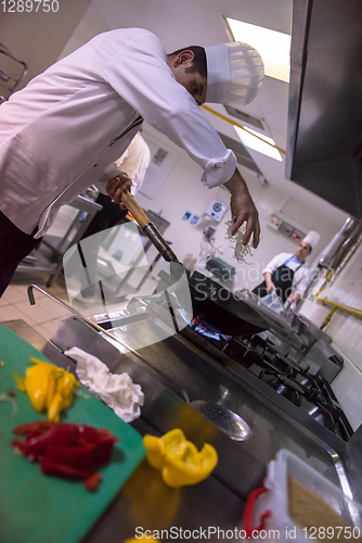 Image of chef preparing food, frying in wok pan