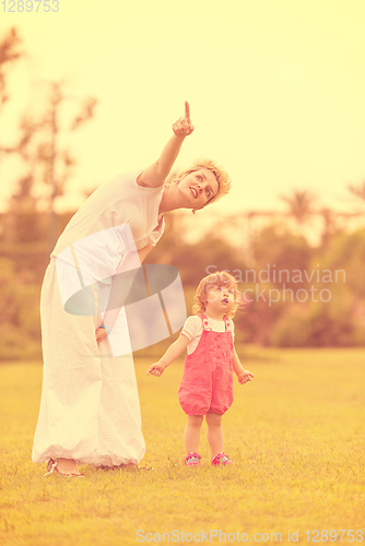 Image of mother and little daughter playing at backyard